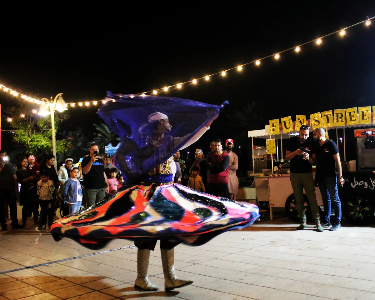 A Tanoura dancer spinning at night with a colourful layered skirt